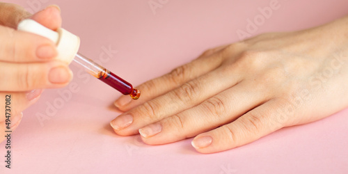 Moisturizing oil for cuticles. The woman cares for hands and nails. Woman applying oil from pipette to cuticle on light background. healthy nails. nail care. beauty concept. High quality photo
