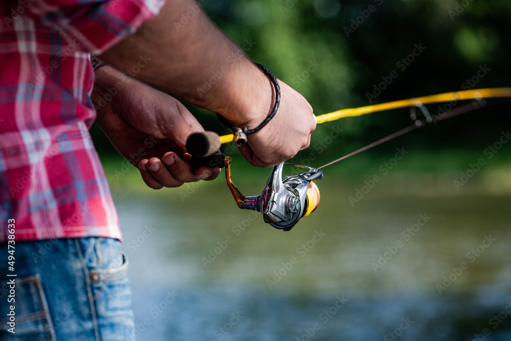 Fishing Reel. Fishing Rod with Aluminum Body Spool. Fishing Gear. Fish  Supplies and Equipment. Fishings reel close-up on the background of the  river Stock Photo