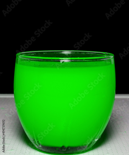 Photo of green water in the glass on black background