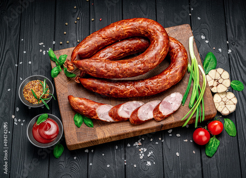 Appetizing smoked pork sausage on a dark background photo