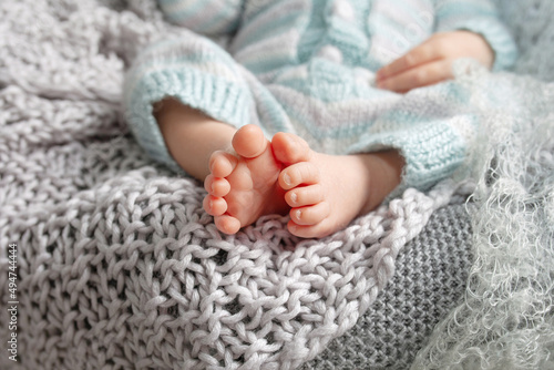 Tiny foot of newborn baby. Soft newborn baby feet against a beige blanket. Baby feet with toes curled up