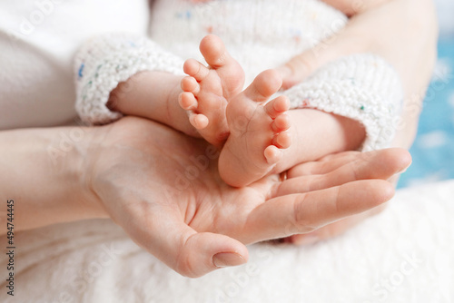 Baby feet in mother hands. Tiny Newborn Baby's feet on female Shaped hands closeup. Mom and her Child. Happy Family concept. Beautiful conceptual image of Maternity