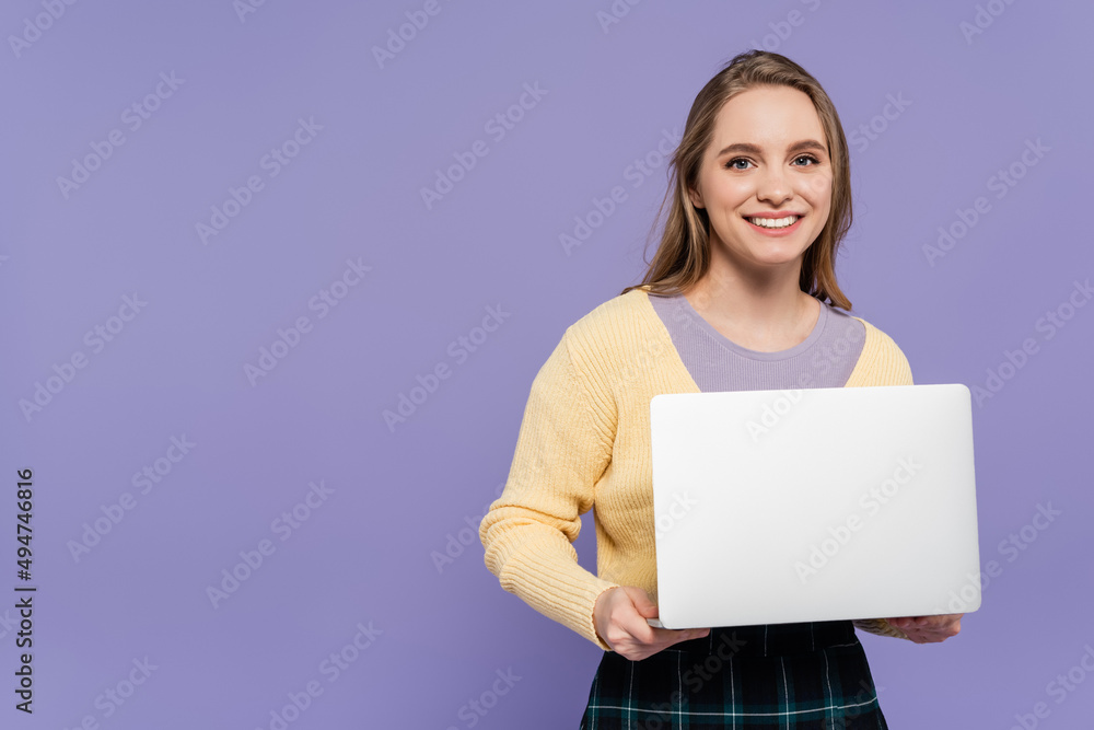 joyful young woman holding laptop isolated on purple. joyful young woman holding laptop isolated on purple.