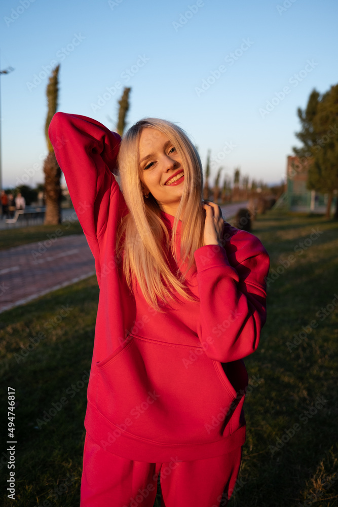 Happy smiling blonde girl in a pink fleece tracksuit has a good time outdoors. The joy of active recreation. High quality photo Happy smiling blonde girl in a pink fleece tracksuit has a good time outdoors. The joy of active recreation. High quality photo