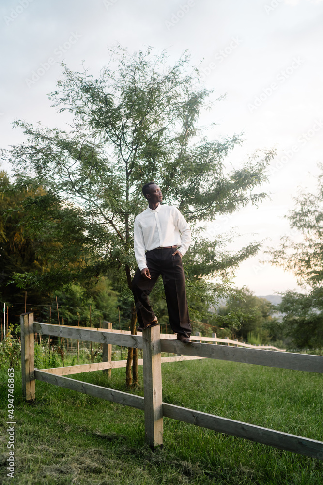Man standing along the road fence. African keeps balance on the log. Man standing along the road fence. African keeps balance on the log.