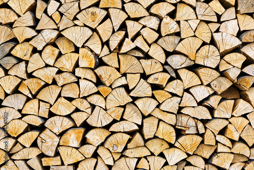 Stacked chopped wood close-up texture. Firewood storage background. Stocks of wooden logs. Chopping wood for a fireplace. Woodpile with firewood with visible wooden texture.