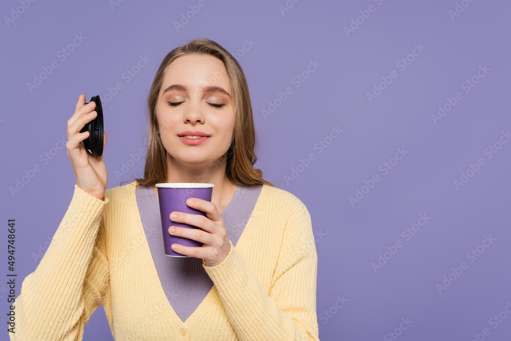 young woman smelling coffee to go in paper cup isolated on purple. young woman smelling coffee to go in paper cup isolated on purple.