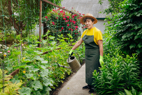Portrait of a Senior woman gardener in a hat working in her yard. The concept of gardening, growing and caring for flowers and plants.