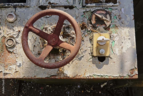  Old decayed control panel with rusty metal steering wheel and bakelite turning knobs and peeling paint  photo