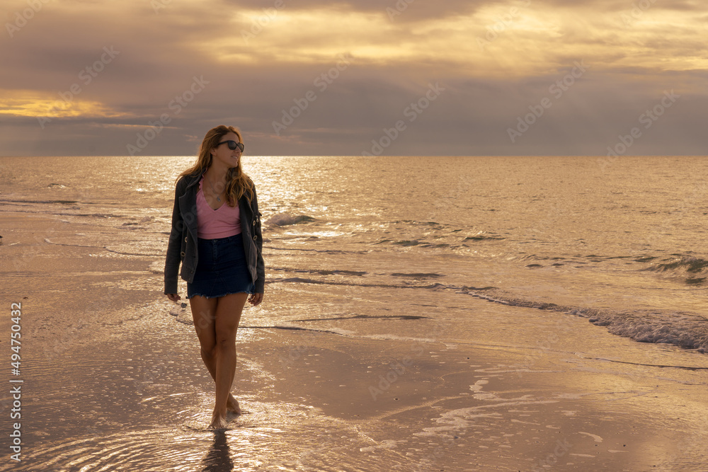 Young blonde woman laughing on the beach at sunset
