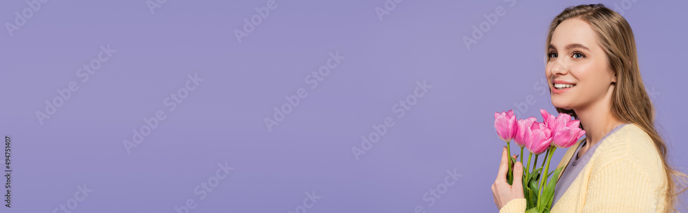 cheerful young woman holding pink tulips isolated on purple, banner. cheerful young woman holding pink tulips isolated on purple, banner.