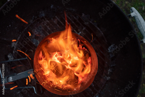 Looking down into the burning charcoal of a Chimney Starter on a backyard grill
