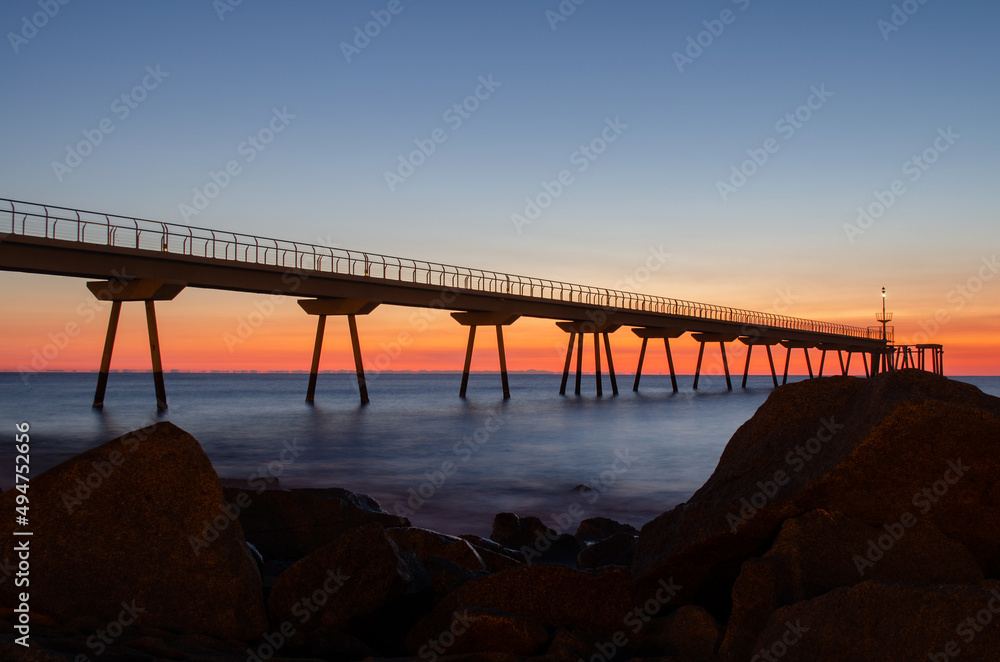 Petroleum bridge next to rocks over the mediterranean sea at dawn one winter morning