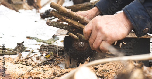 Man cutting wood using stationary circular saw outdoors in winter for kindling close-up view