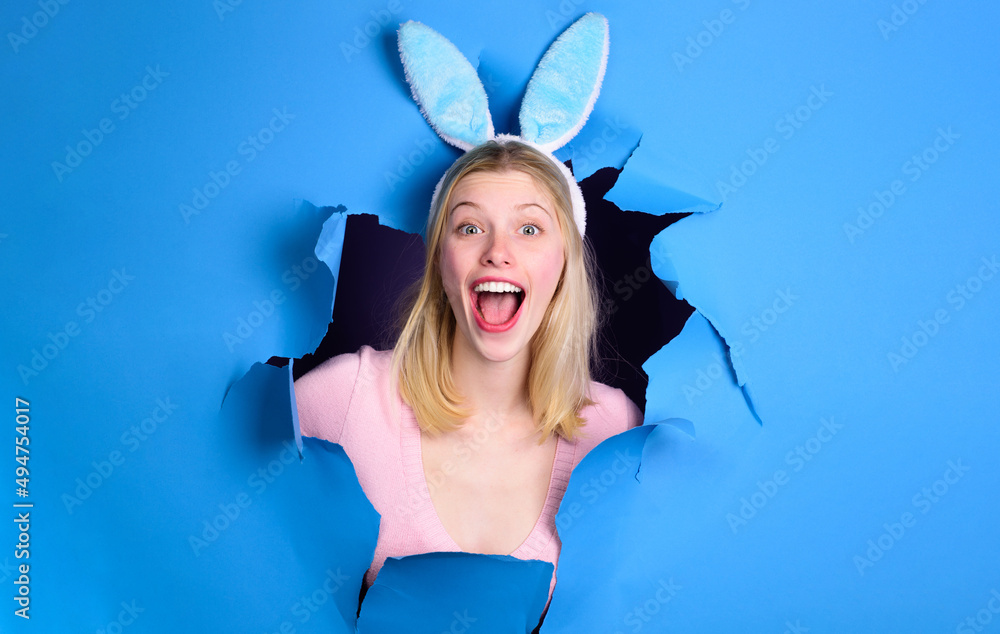Happy Easter Day. Smiling Woman in bunny ears looking through paper hole. Rabbit girl on holiday. Happy Easter Day. Smiling Woman in bunny ears looking through paper hole. Rabbit girl on holiday.