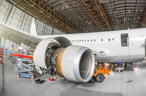 Passenger aircraft on maintenance of engine and fuselage repair in airport hangar. View airplane engine. photo