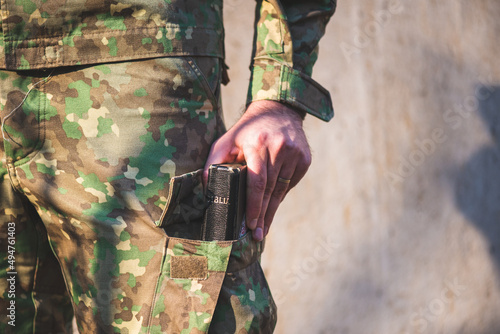 Soldier dressed in camouflage uniform with a bible in his foot pocket