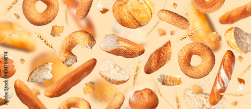 Creative food concept. Various types of bread, ears of wheat flying on beige background. Classic wheat round bread, baguette, bun, sesame bagel. Organic Healthy Fresh bread for bakery advertising