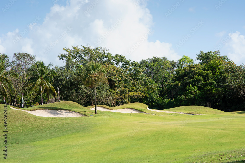 Panoramic view of a golf course with sand bunkers surrounded by tropical plants in Mexico