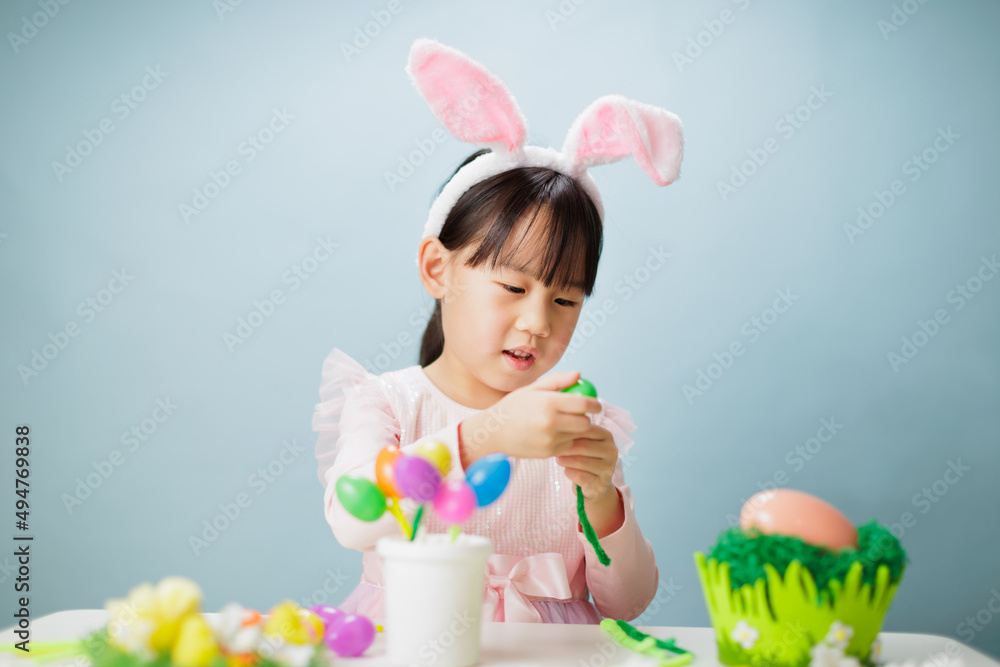 young girl making easter craft against plain background young girl making easter craft against plain background