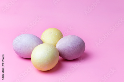 easter eggs in yellow and purple on a pink background with space for text