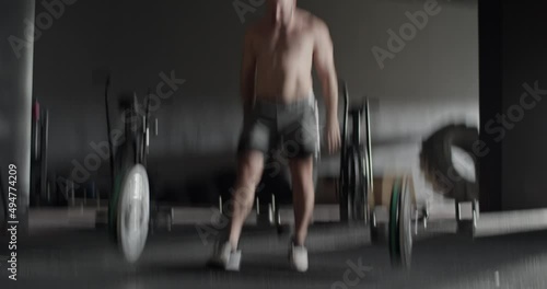 Muscular sportsman doing snatch exercise with barbell