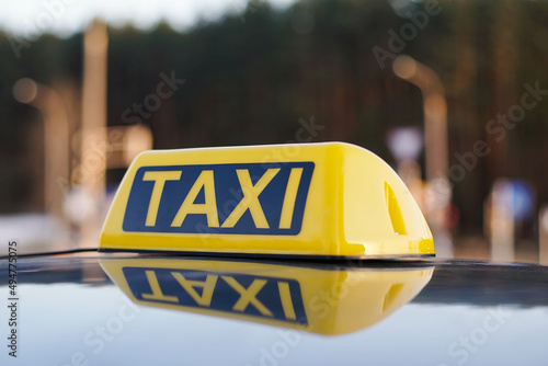 Close Up Of Taxi Cab Sign On a Car Roof. Daytime Traffic On The Background.