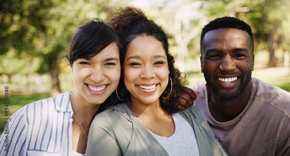 Smiles all around on a beautiful day. Portrait of a group of friends posing together while relaxing in a park outdoors. Smiles all around on a beautiful day. Portrait of a group of friends posing together while relaxing in a park outdoors.