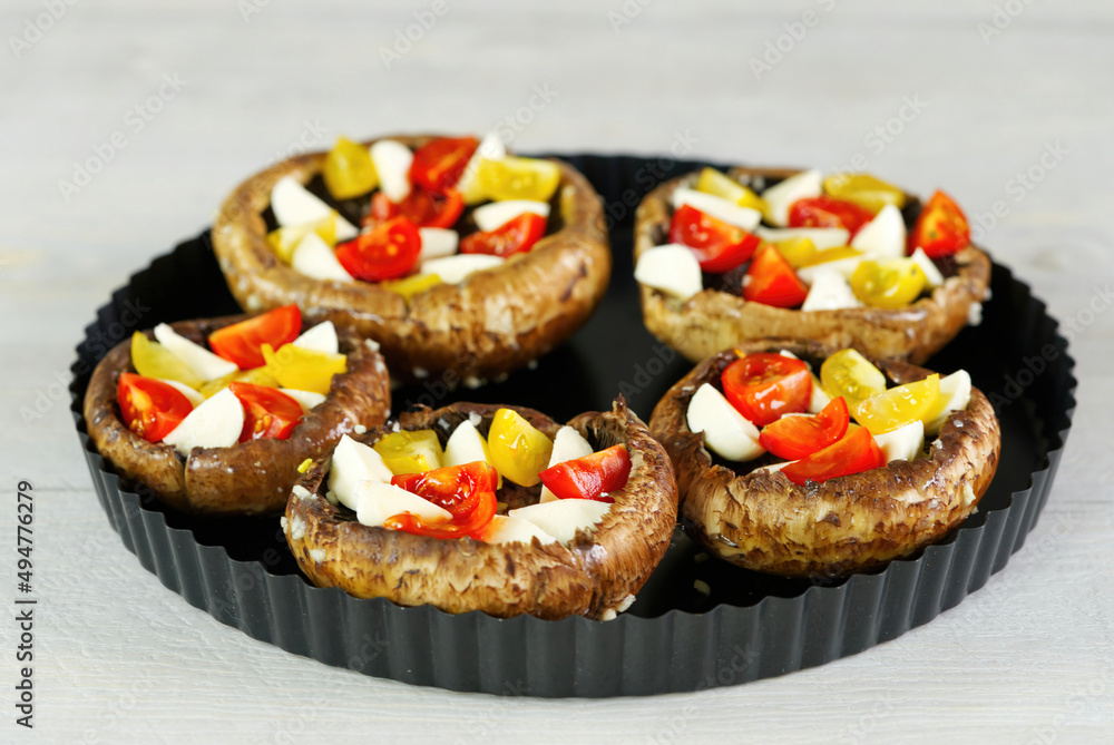 raw champignons stuffed with cheese, tomatoes and paprika in a baking dish. close up raw champignons stuffed with cheese, tomatoes and paprika in a baking dish. close up