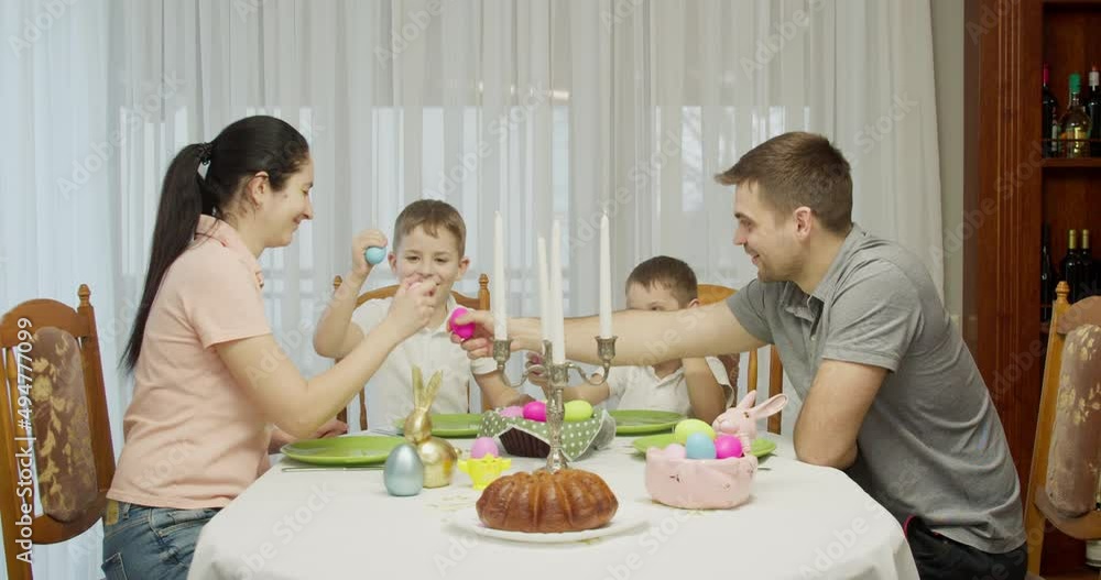 Happy Easter. mom, dad and kids having fun hitting holiday eggs Happy Easter. mom, dad and kids having fun hitting holiday eggs
