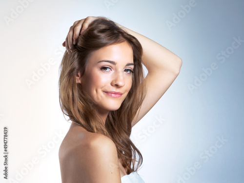Fresh and free. Studio portrait of a beautiful young woman with her hand in her hair.