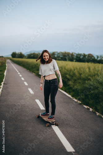 Young stylish girl with skateboard standing outdoors. 