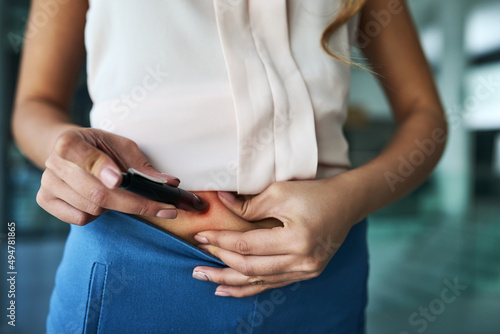 Taking the measures to keep her health under control. Closeup shot of an unidentifiable businesswoman injecting her stomach.