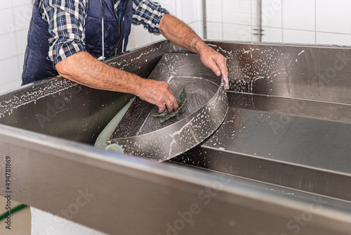 unrecognisable elderly worker scrubbing a piece of metal with a scouring pad