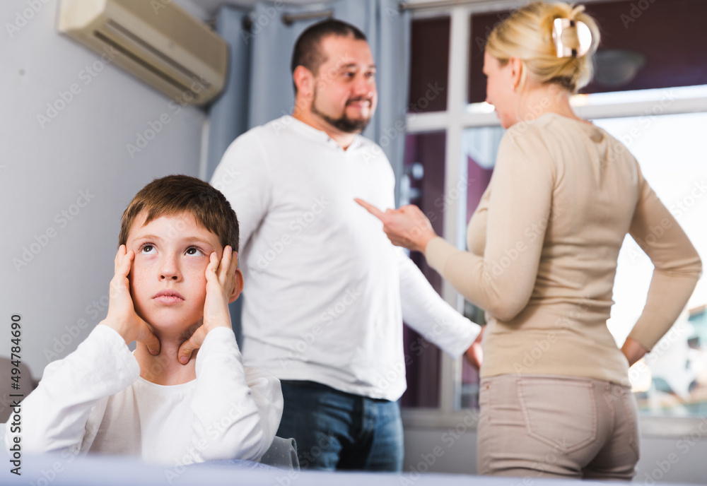 Obraz premium Sad desperate little boy during parents quarrel in home interior