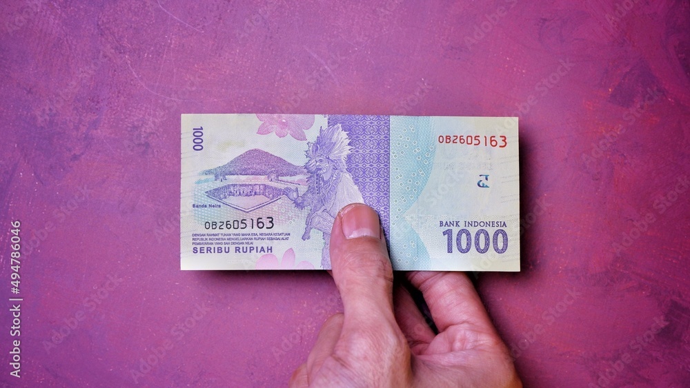Fototapeta premium Indonesian Rupiah the official currency of Indonesia. Man's hand is making a payment. Business Loan Income Money Investment Economy and Finance Concept Uang 1000 1.000 Rupiah. Prosperity Concept.
