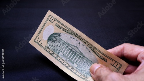 Businessman's hand holding American Dollar Banknotes, isolated on black background. Business Investment Economy Saving Loan Income Money and Finance concept. Ten Dollar,  10 USD. Prosperity concept.