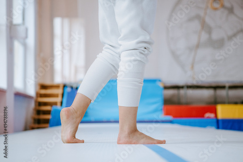 Close up of female hands touching safety mat, woman practicing gymnastic in gym. Detail woman foots photo