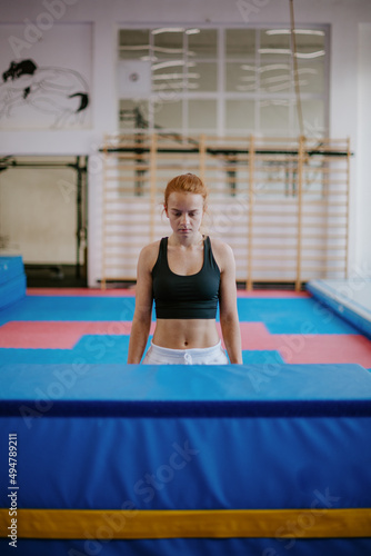 young gymnastic woman is standing in front of an obstacle and getting ready to jump