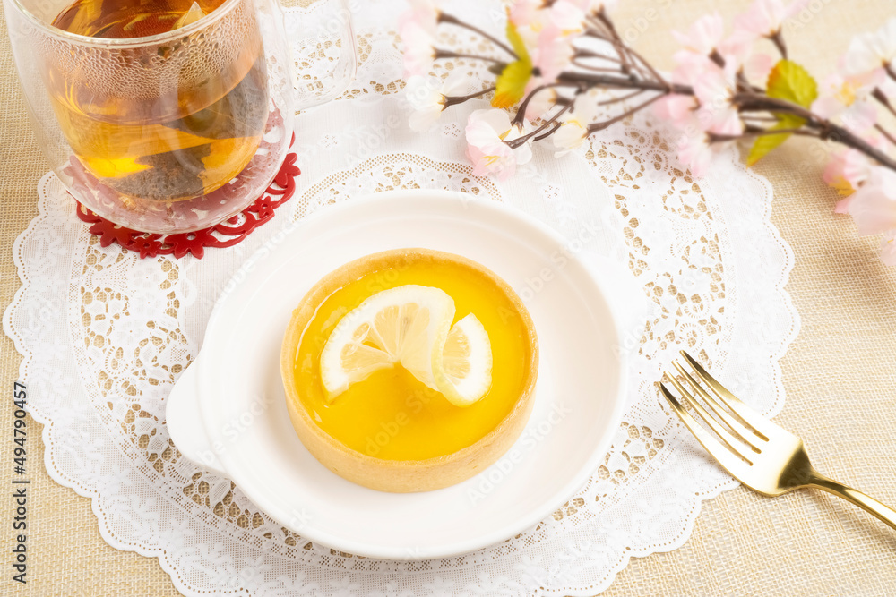 Fresh baked Lemon Tart topping with lemon sliced, served with hot tea on white placemat, good for teatime Fresh baked Lemon Tart topping with lemon sliced, served with hot tea on white placemat, good for teatime