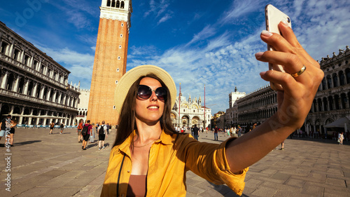 Blogger girl Venice. Travel photographer woman with smartphone in Venice San Marco square. Paint building house in Europe Venezia city. Freelancer, journalist, professional photographer.