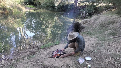 A bush man cooks bacon on a camp fire on the side of a creek in rural Victoria Australia. photo