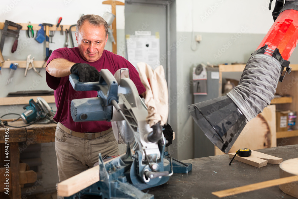 Carpenter cutting a wooden workpiece on an electical circular saw