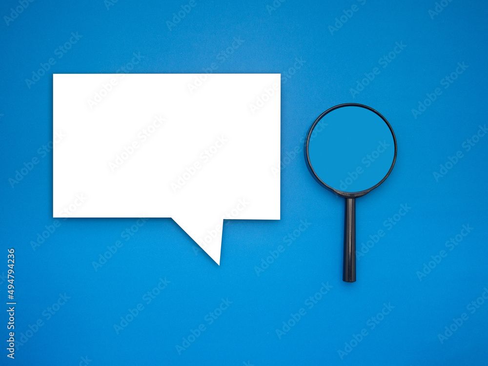 Top view of a blank speech bubble and a magnifying glass on a blue background Top view of a blank speech bubble and a magnifying glass on a blue background