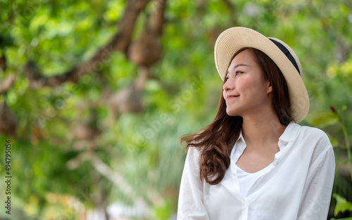 Portrait image of a beautiful young asian woman in white shirt with hat relaxing in the park © Farknot Architect