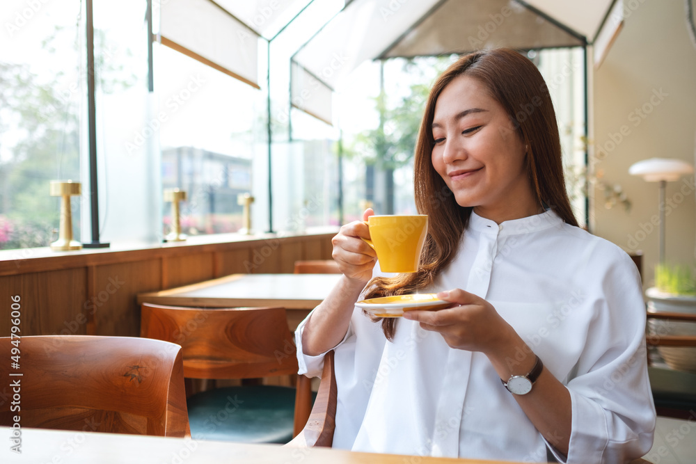 Portrait image of a beautiful young asian woman holding and drinking coffee in cafe Portrait image of a beautiful young asian woman holding and drinking coffee in cafe