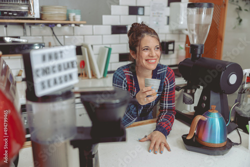 Smiling barista holding cup of coffee in cafe
