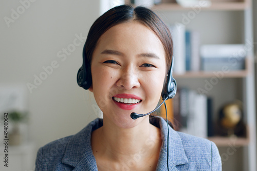 Close up of Young Asian businesswoman wearing headphone, call center, customer service and smiling. Look at camera photo