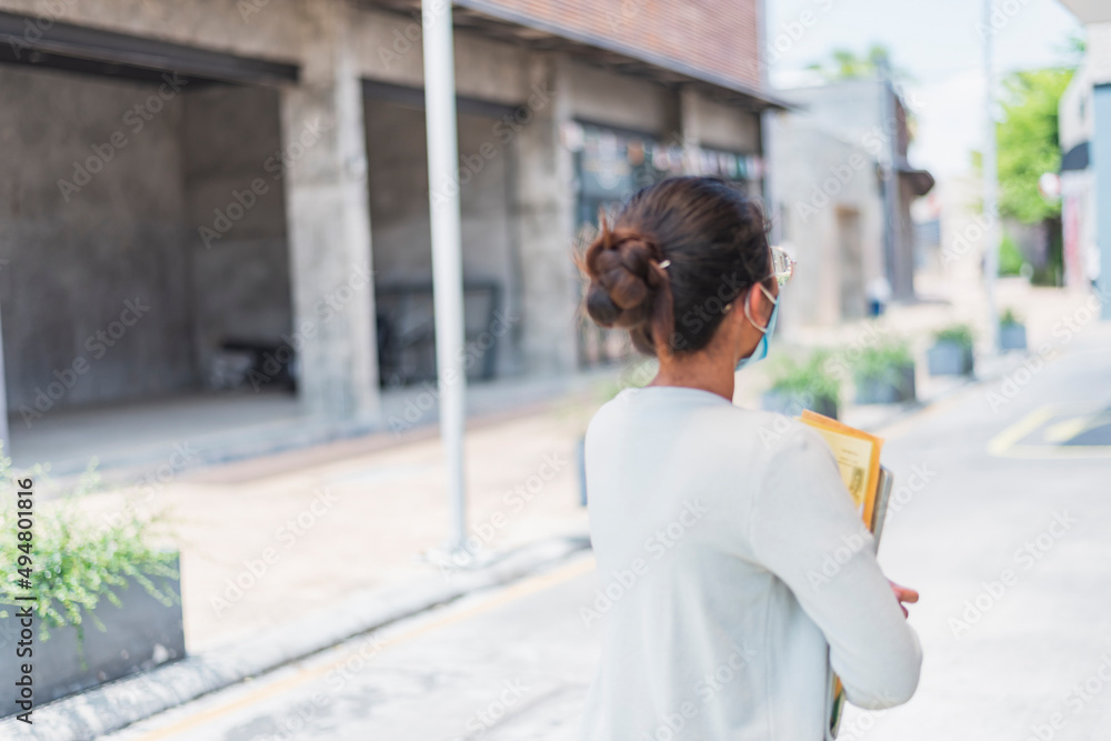A middle-aged businesswoman commuting to her office during the outbreak or after the COVID-19 measures have eased. A businesswoman wears a mask. A middle-aged businesswoman commuting to her office during the outbreak or after the COVID-19 measures have eased. A businesswoman wears a mask.