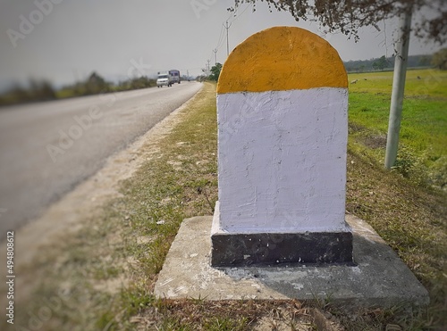 A blank yellow and white color milestone on the international highway. Milestone with space for writing photo